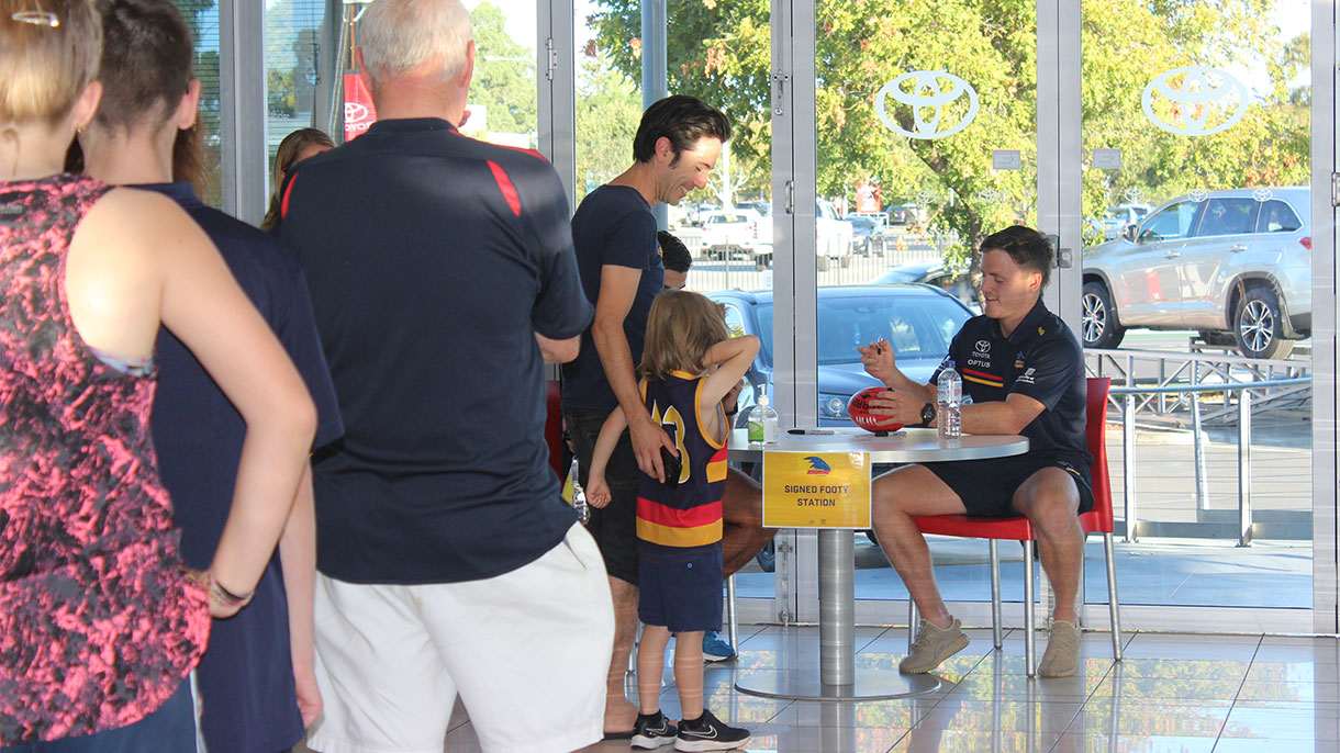 Adelaide Crows players signing footballs