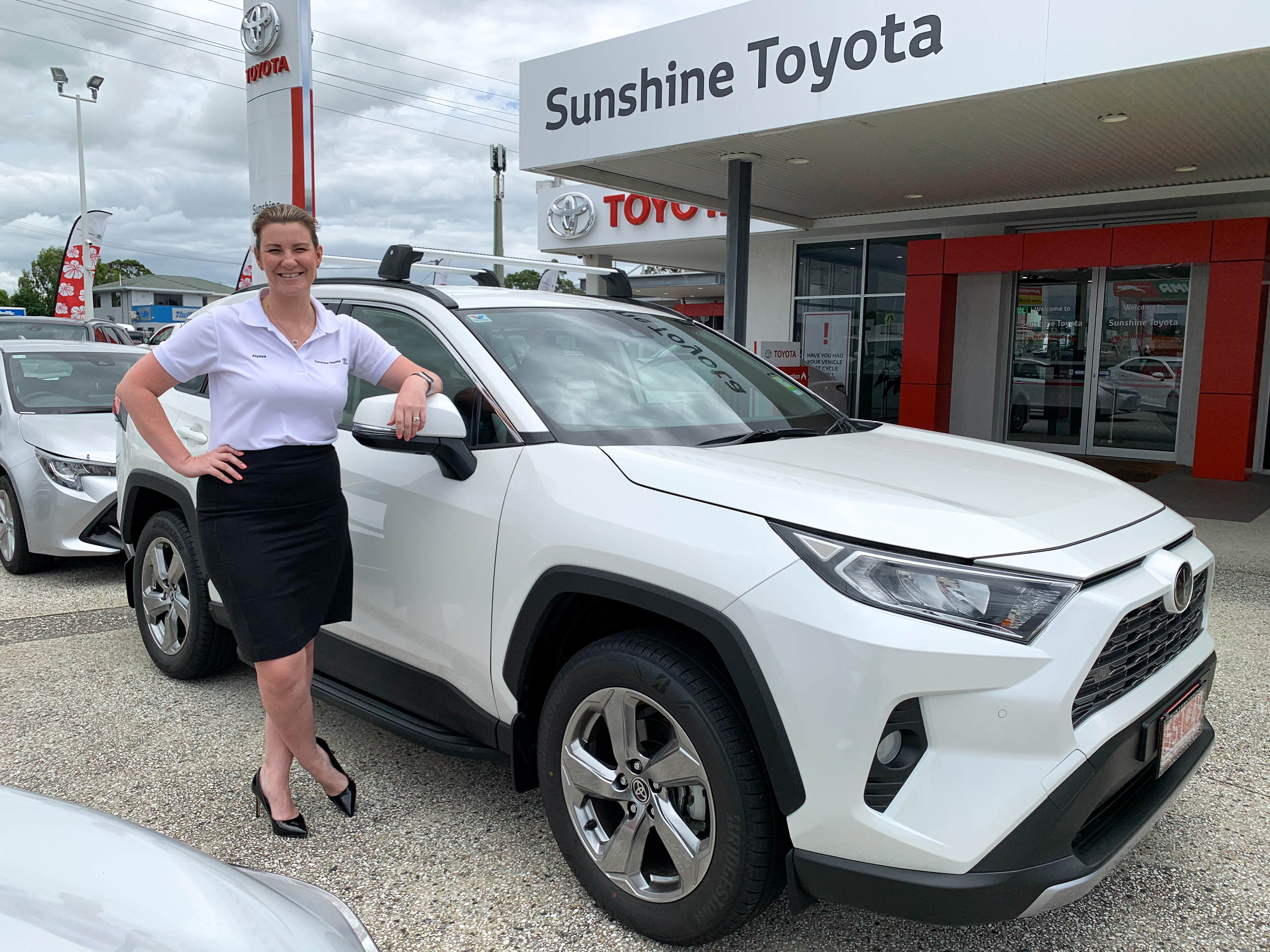 Alyssa with a white hybrid Rav4 - ask us today at Sunshine Toyota on the Sunshine Coast
